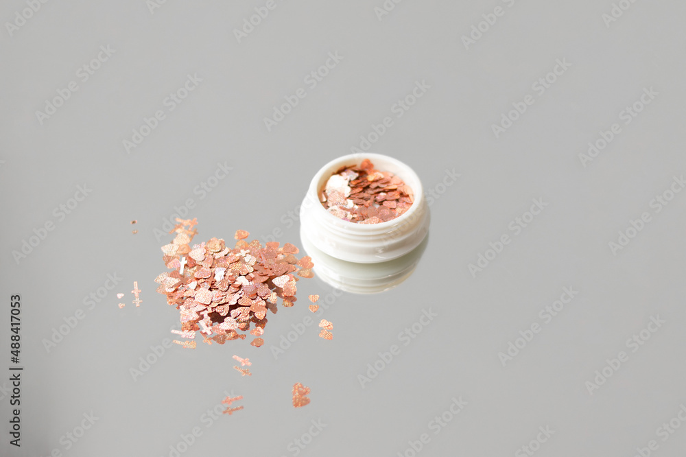 Glitter for nails and body.Beautiful glitter for nails and body close-up. Gold glitter on gray background Glitter for nails and body.Beautiful glitter for nails and body close-up. Gold glitter on gray background
