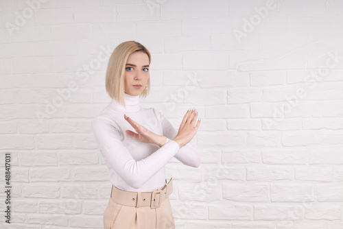 Break the bias symbol of woman's international day. The arms of a girl in white are crossed on a white brick wall. Woman arms crossed to show solidarity, breaking stereotypes, inequality
 photo