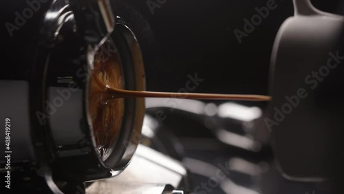 Slow motion vertical shot of espresso extraction with bottomless portafilter photo