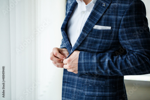 Young male businessman puts on a shirt and a stylish suit before a meeting