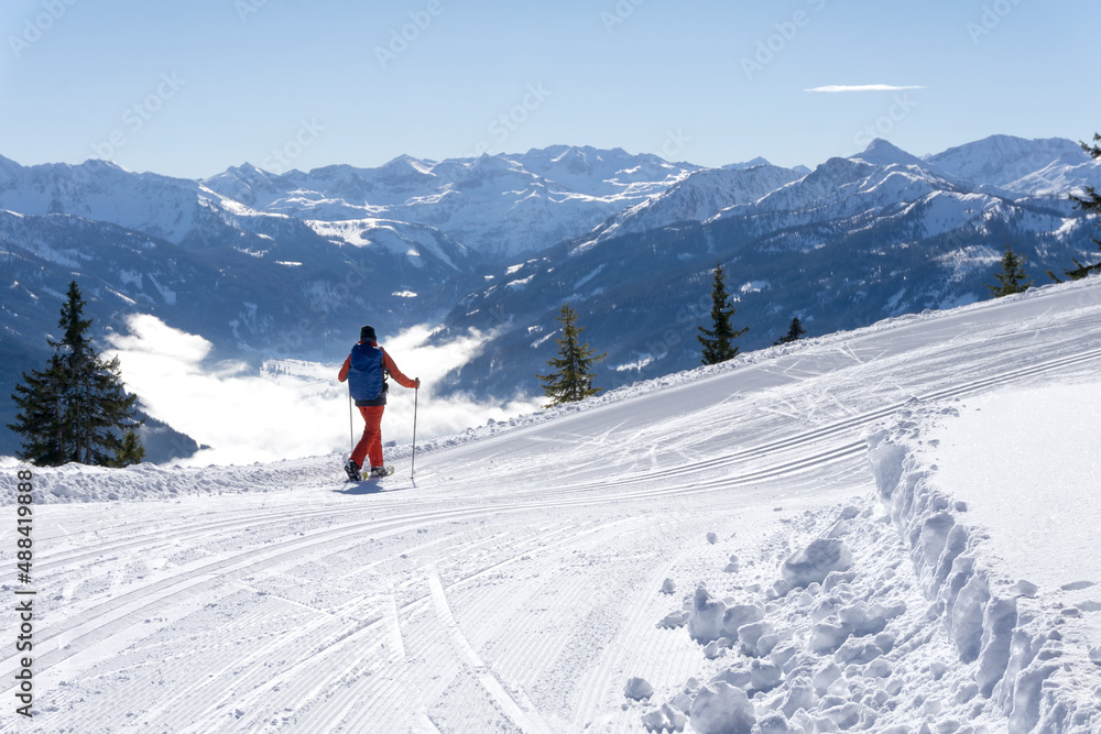 Mountain winter landscape, Salzburg Alps, Austria, Europe.A lonely hiker wanders around the Rossbrand peak on snowshoes admiring the scenic view of the valley and the surrounding area.