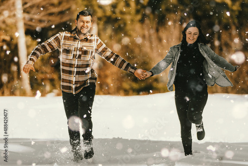 Couple running and holding hands in the winter snowy forest. Selective focus photo