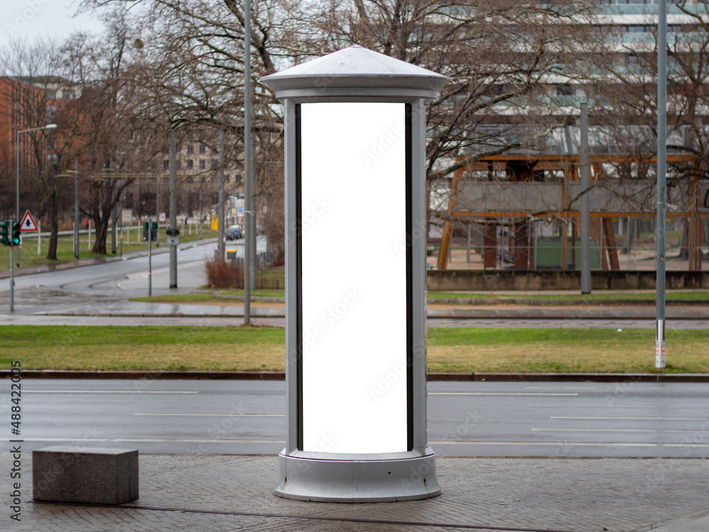 Advertising column in the city. Blank mockup for testing ad designs on the pillar next to the street. Billboard template with a white rectangle in a city. Copy space in an urban area for marketing. Advertising column in the city. Blank mockup for testing ad designs on the pillar next to the street. Billboard template with a white rectangle in a city. Copy space in an urban area for marketing.