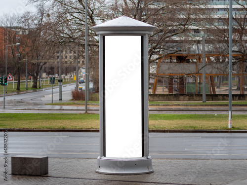 Advertising column in the city. Blank mockup for testing ad designs on the pillar next to the street. Billboard template with a white rectangle in a city. Copy space in an urban area for marketing.