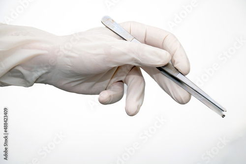 Quadro su tela Forceps in doctor hand with disposable glove on white background.