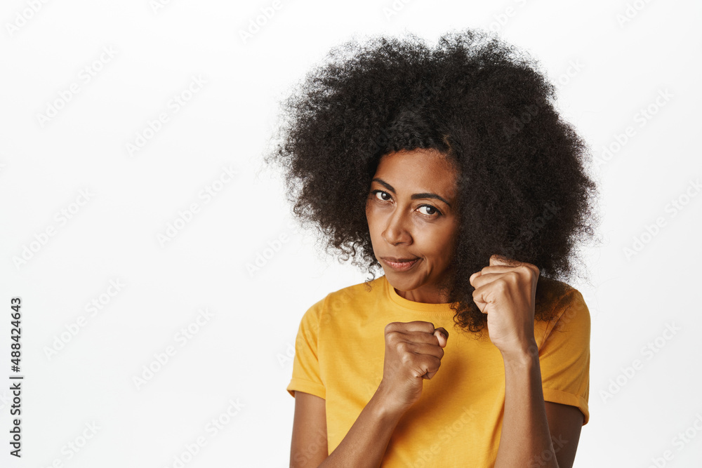 Ready to fight. Sassy african american lady showing punch, fists gesture, fighting, restle with someone, standing in yellow t-shirt over white background Ready to fight. Sassy african american lady showing punch, fists gesture, fighting, restle with someone, standing in yellow t-shirt over white background