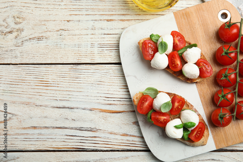 Delicious sandwiches with mozzarella, fresh tomatoes and basil on white wooden table, flat lay. Space for text Delicious sandwiches with mozzarella, fresh tomatoes and basil on white wooden table, flat lay. Space for text