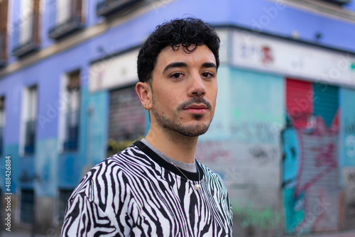 Fotografía Young hispanic man with serious expression standing at the city