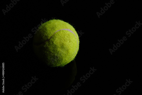 Green tennis ball at black background. Low key photo with copy space © Philipp Berezhnoy