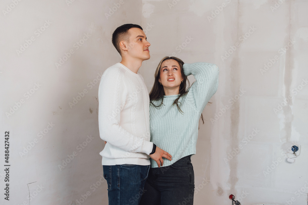 Couple in unfinished building. Woman and men thinking about apartment renovation. Young couple in new property.Family buy new flat.
