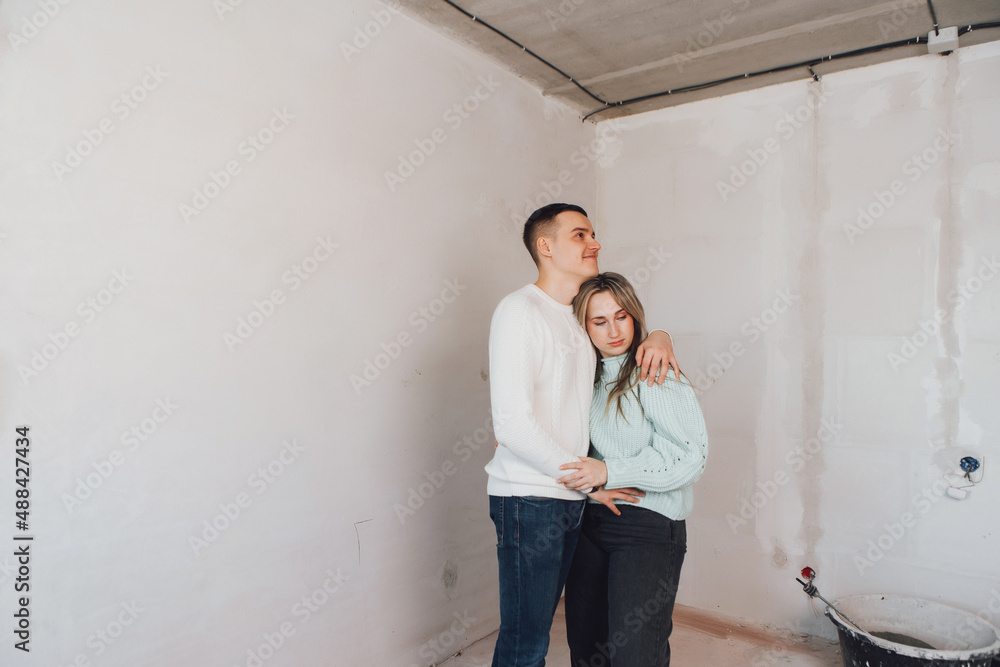 Couple in unfinished building. Woman and men thinking about apartment renovation. Young couple in new property.Family buy new flat.
