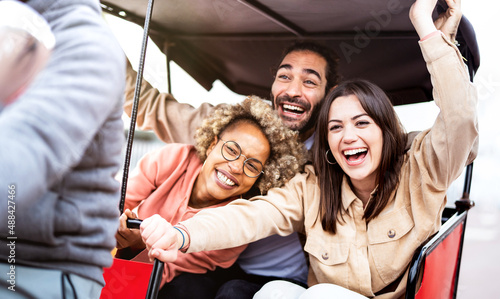Multiracial students cheering on rickshaw at travel location - Life style concept with guys and girls having fun together - College mates riding around the city after school vacations - Bright filter photo