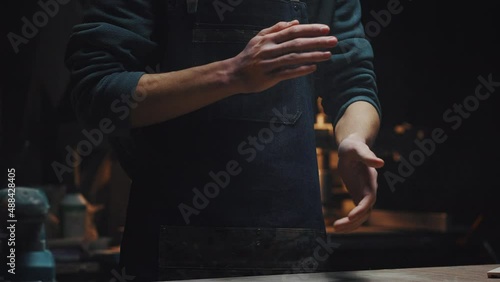 Young unrecognizable guy in workshop, dark key. Cinematic video close-up of male hands shake off dust and shavings. A man completes work, men's work, male hobby concept photo