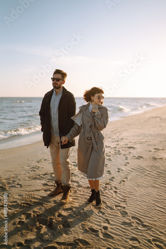 Stylish couple walking and hugging by the sea. Springtime. Relaxation, youth, love, lifestyle solitude with nature.