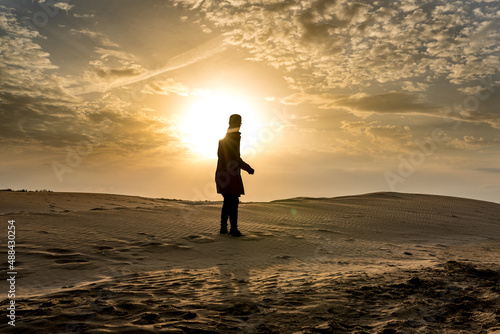 Silhouette of a man on the dunes at sunset. Desert and sand.