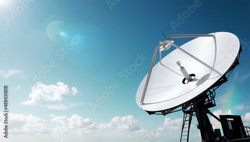 Canvas Print Big parabolic antenna with lens flare sun against sky