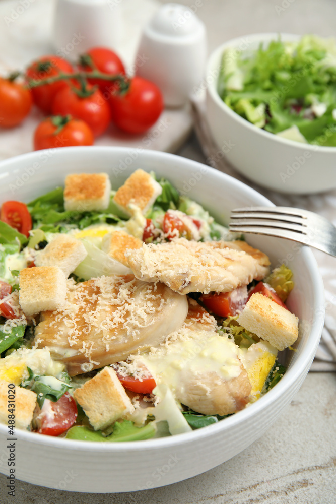 Delicious fresh Caesar salad in bowl on light grey table, closeup Delicious fresh Caesar salad in bowl on light grey table, closeup