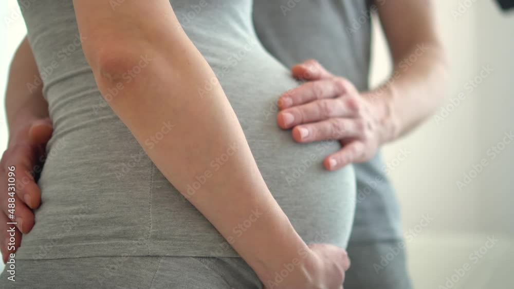 Pregnant woman and her husband holding hand together. Young family is happy in anticipation of a baby, parenthood. Two hands holding baby inside a pregnant woman Pregnant woman and her husband holding hand together. Young family is happy in anticipation of a baby, parenthood. Two hands holding baby inside a pregnant woman
