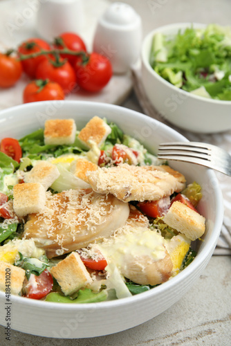 Delicious fresh Caesar salad in bowl on light grey table, closeup