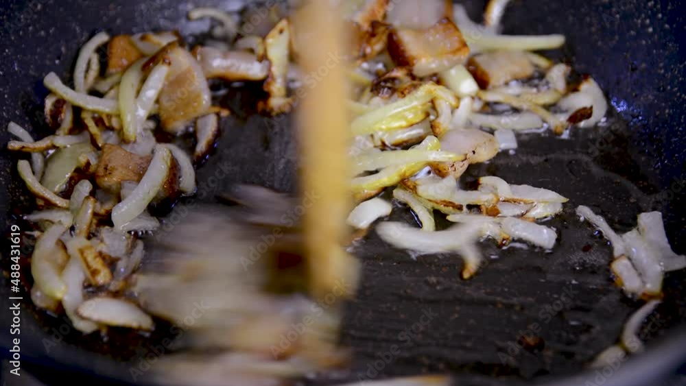 Salo and finely chopped onion are fried in a black frying pan. Eggs are