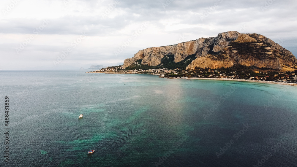Drone shot of a bay with cliffs and mountains. Bay in Italy. Aerial view of Mondello Beach bay, Palermo, Sicily.