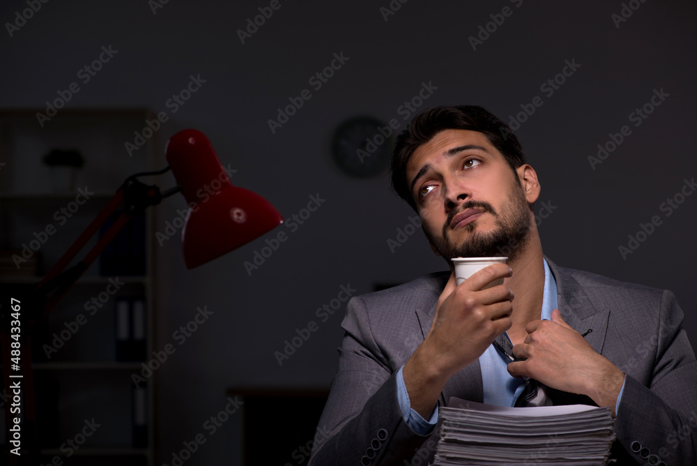 Naklejka premium Young male employee working late in the office