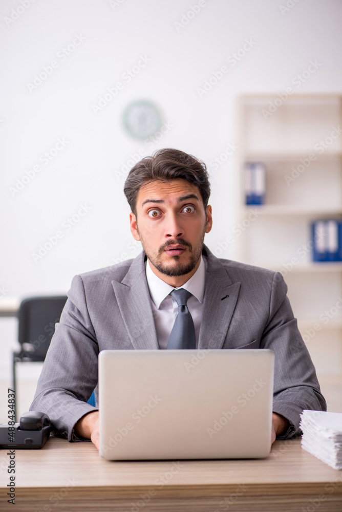 Young male employee and too much work in the office Young male employee and too much work in the office