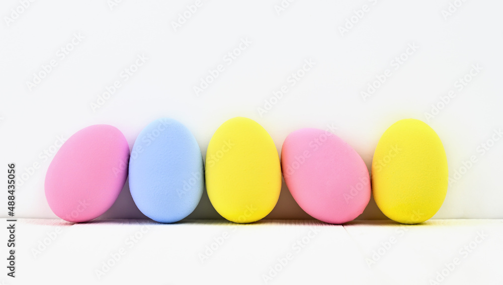 Many colored Easter eggs stand on a light background with copy space Many colored Easter eggs stand on a light background with copy space