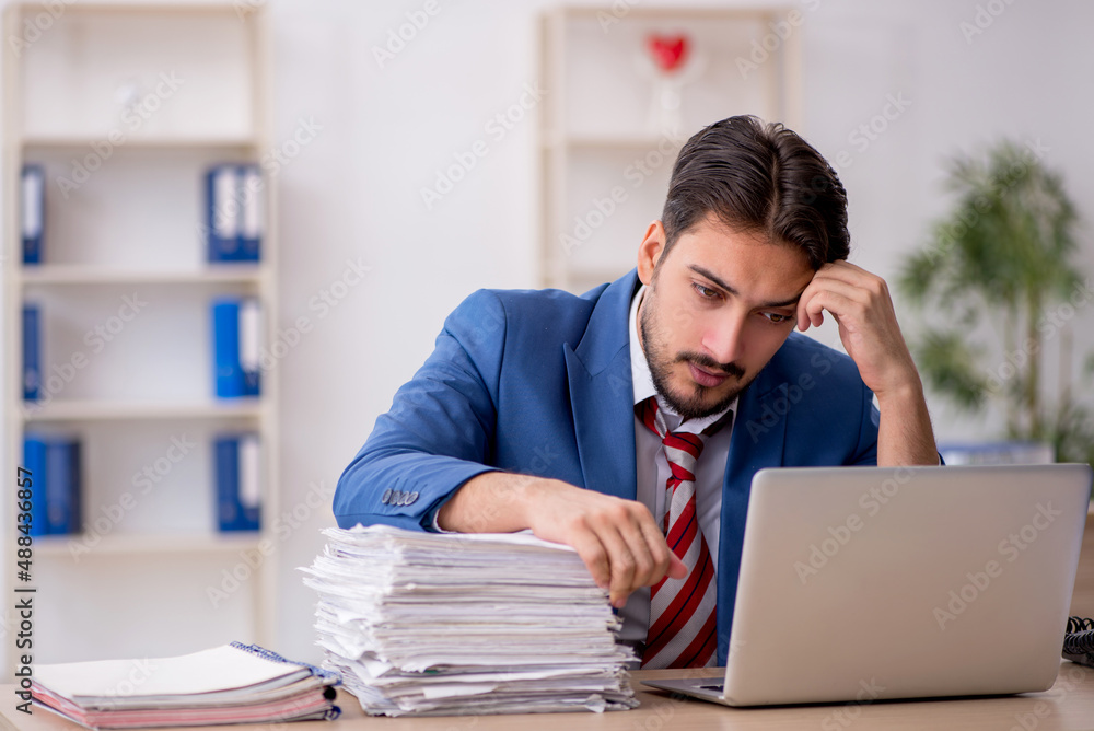 Young male employee and too much work in the office Young male employee and too much work in the office