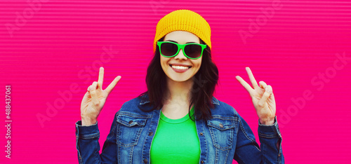 Summer portrait of happy smiling young woman wearing a colorful clothes, hat on pink background