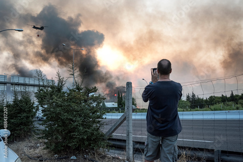 ATHENS, GREECE-03 AUGUST 2021: A man is taking photos/video of the wildfire that raged uncontrolled, near the national motorway the north suburbs of Athens. Part of it was sealed off by the authoritie