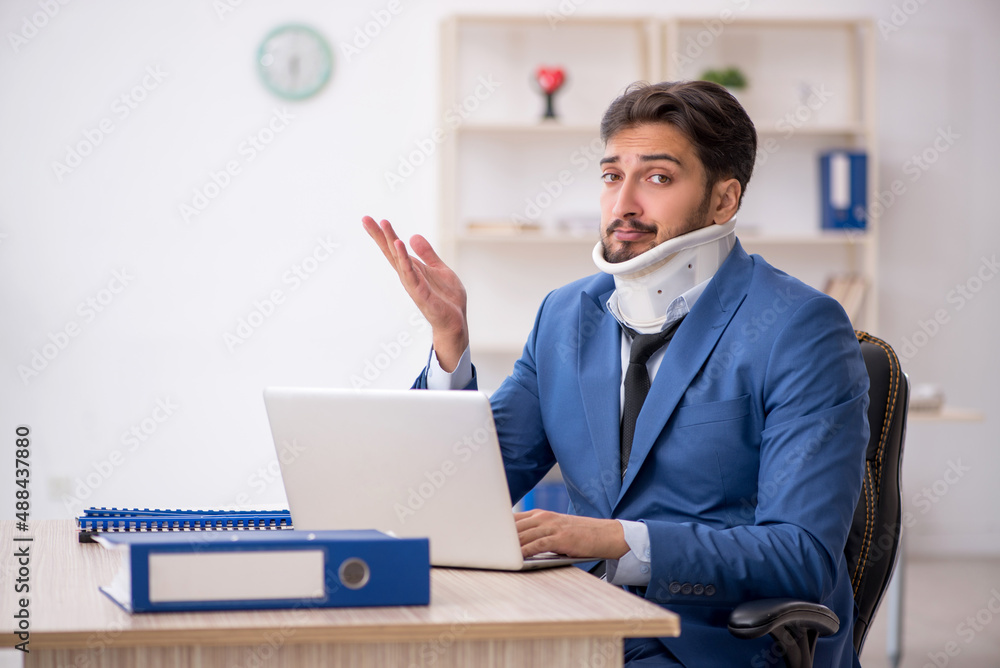 Young neck injured male employee sitting in the office Young neck injured male employee sitting in the office