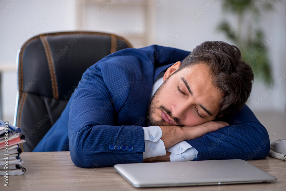 Young male employee extremely tired in the office Young male employee extremely tired in the office