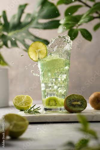 Wallpaper Mural A green refreshing beverage with kiwi, lime and ice cubes in tall long glass with splashes on marble board in green plants setting Torontodigital.ca