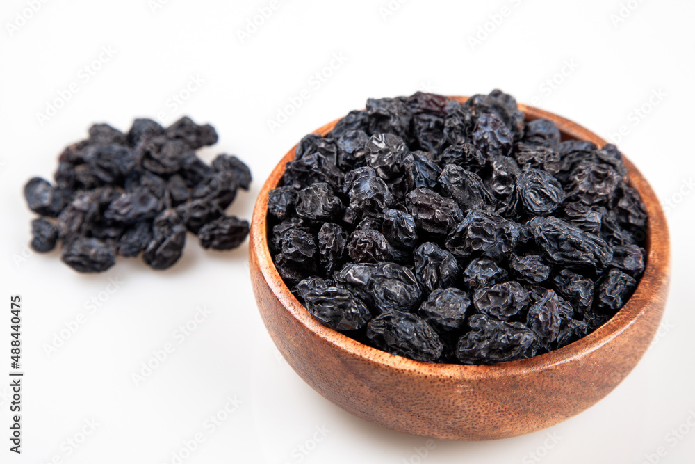 Black raisins full wooden bowl, top view Black raisins full wooden bowl, top view