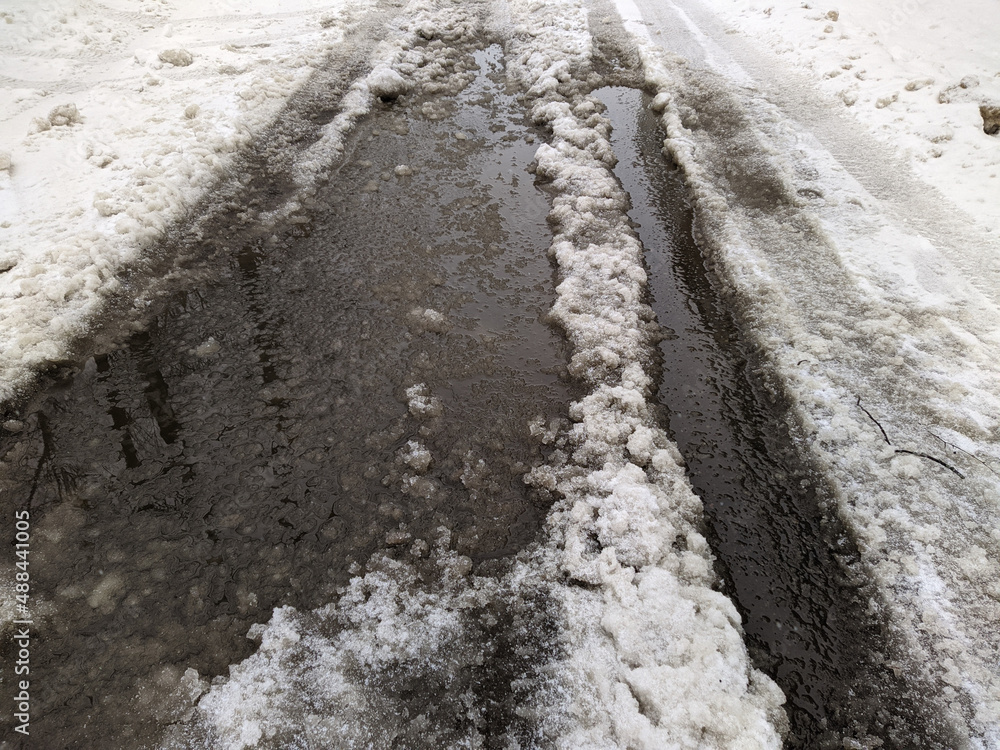 Fototapeta premium melted dirty snow on city streets photo in the daytime.