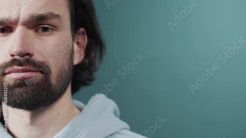 Isolated dark-haired guy confused feels doubt while makes choice, dressed in casual hoodie
