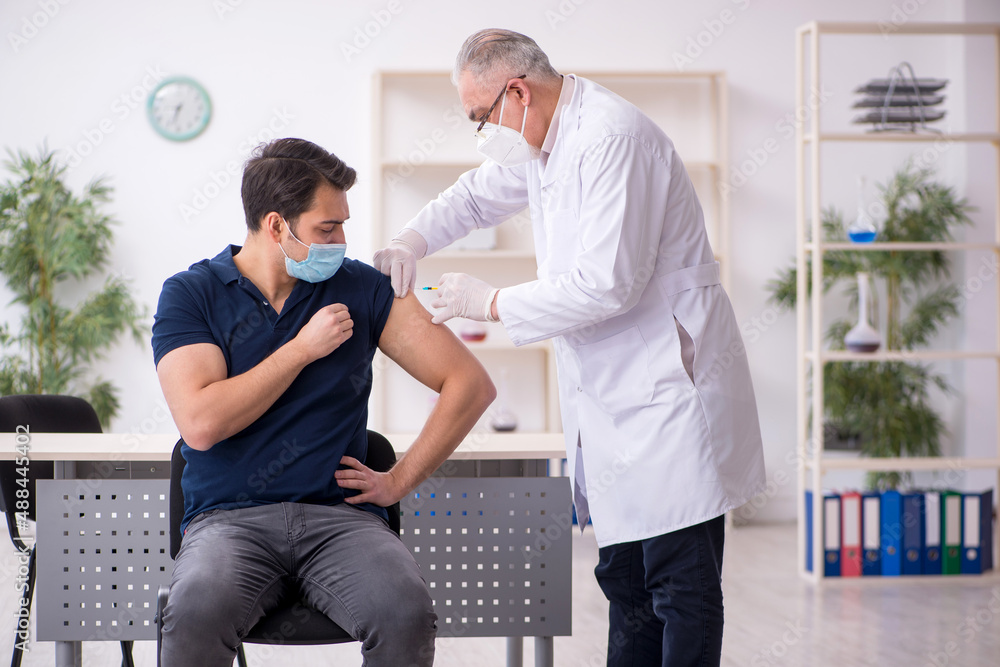 Obraz premium Young male patient visiting old male doctor in vaccination conce