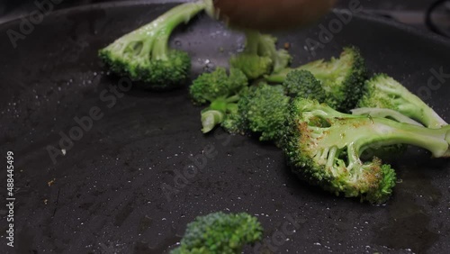 mixing broccoli with wood spoon on oil fry pan slow motion 4k photo