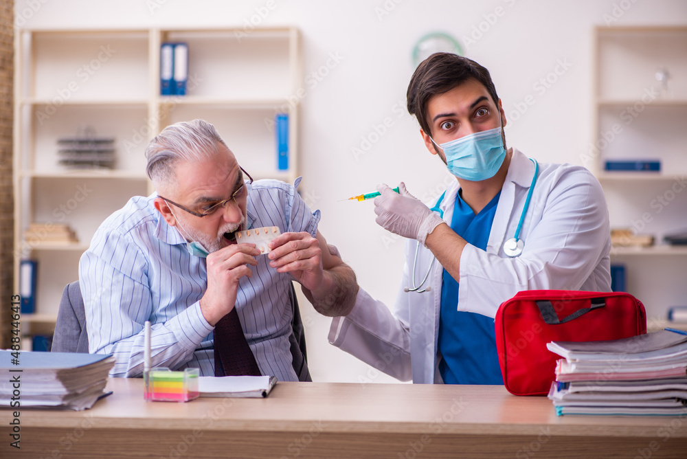 Young male doctor visiting old businessman at workplace Young male doctor visiting old businessman at workplace