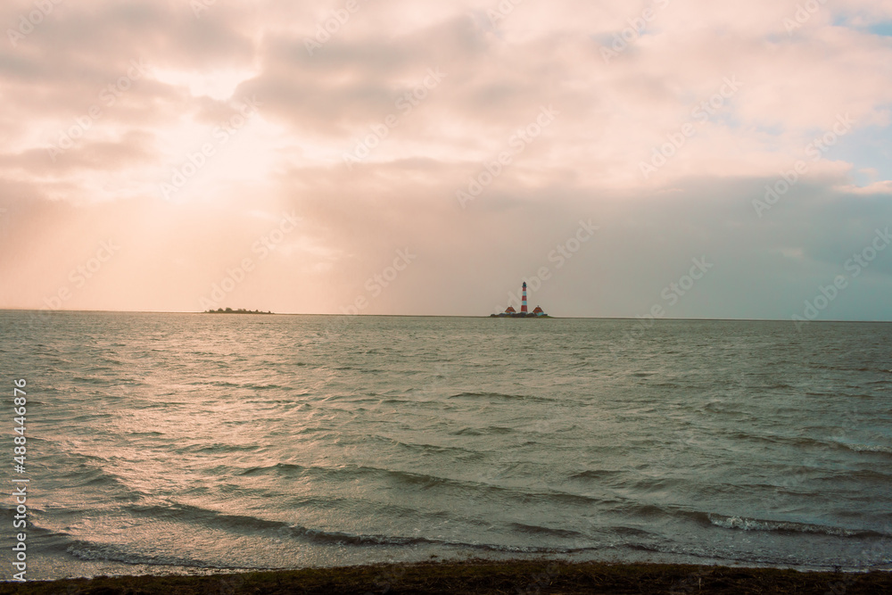 Der große Leuchtturm von Westerhever steht nach einer Sturmflut bei schönem Wetter und Sonne mitten in den Wellen der Nordsee. Der große Leuchtturm von Westerhever steht nach einer Sturmflut bei schönem Wetter und Sonne mitten in den Wellen der Nordsee.