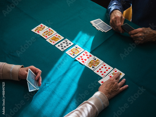 Grandparents hands playing card game in home