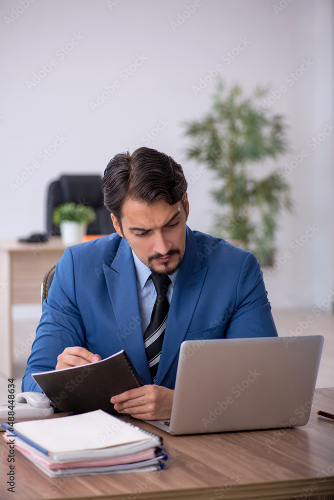 Young male employee unhappy with excessive work in the office Young male employee unhappy with excessive work in the office