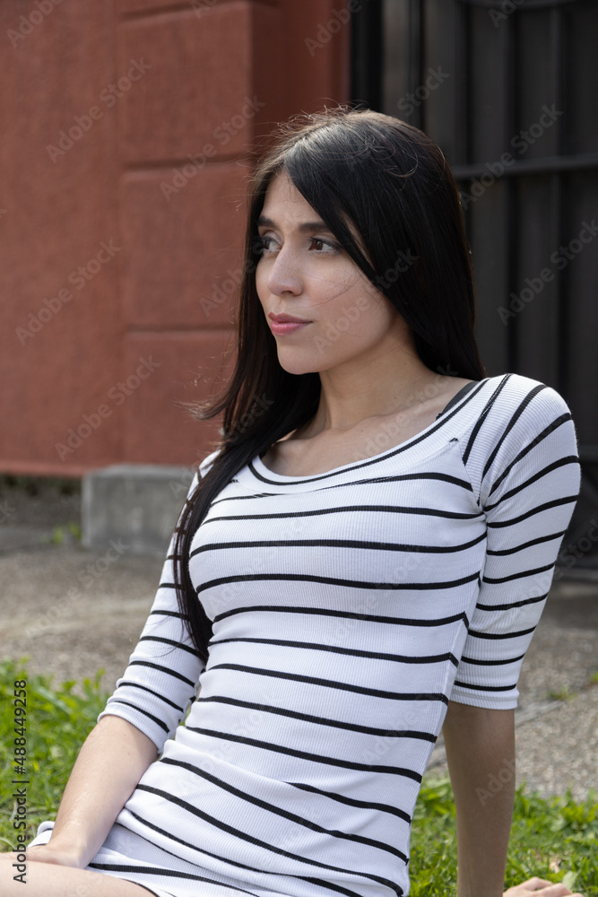 sunny day in a park sitting relaxed young latin woman with straight black hair, female model beauty wearing casual dress while smiling, lifestyle sunny day in a park sitting relaxed young latin woman with straight black hair, female model beauty wearing casual dress while smiling, lifestyle