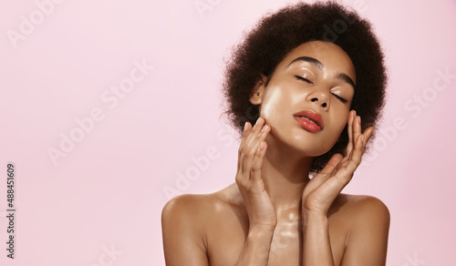 Portrait of beautiful natural african american girl, white sensual clear and fresh face, holding hands near nourished, clean skin, showering and cleansing concept, pink background