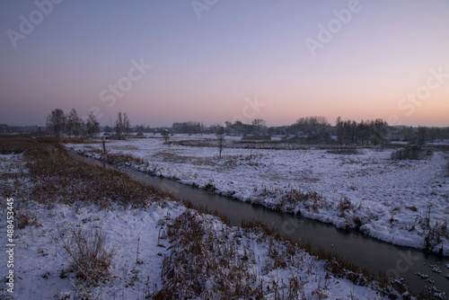 Winter landscape with a river at sunset time.