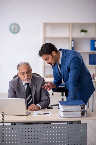Old male boss and young male employee working in the office