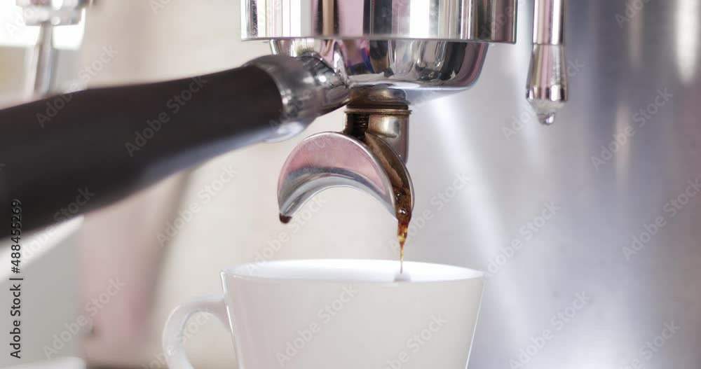 Coffee is pouring into a cup of coffee. Dark coffee drips into the cup from the machine. Coffee is pouring into a cup of coffee. Dark coffee drips into the cup from the machine.