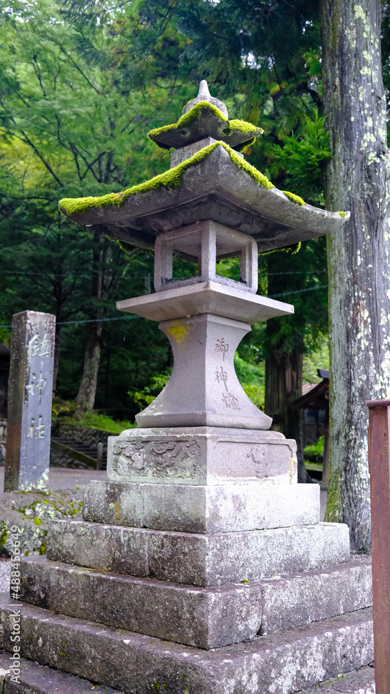 Rustic stone lanterns to moss covered rocks in shrine at Narai juku. Lantern are a symbol of illumination, a guiding light, can be saved from darkness Rustic stone lanterns to moss covered rocks in shrine at Narai juku. Lantern are a symbol of illumination, a guiding light, can be saved from darkness