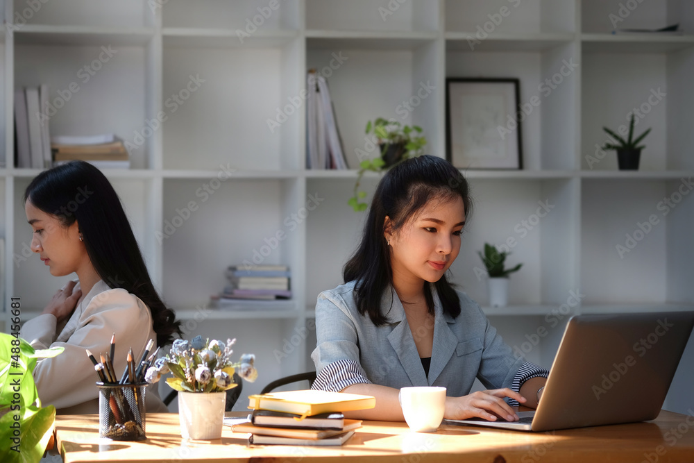 Young asian business woman working with laptop computer while sitting with her colleague in office. Young asian business woman working with laptop computer while sitting with her colleague in office.